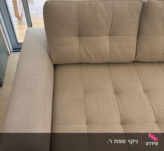ספה נקייה ליד חלון עם אור שמש